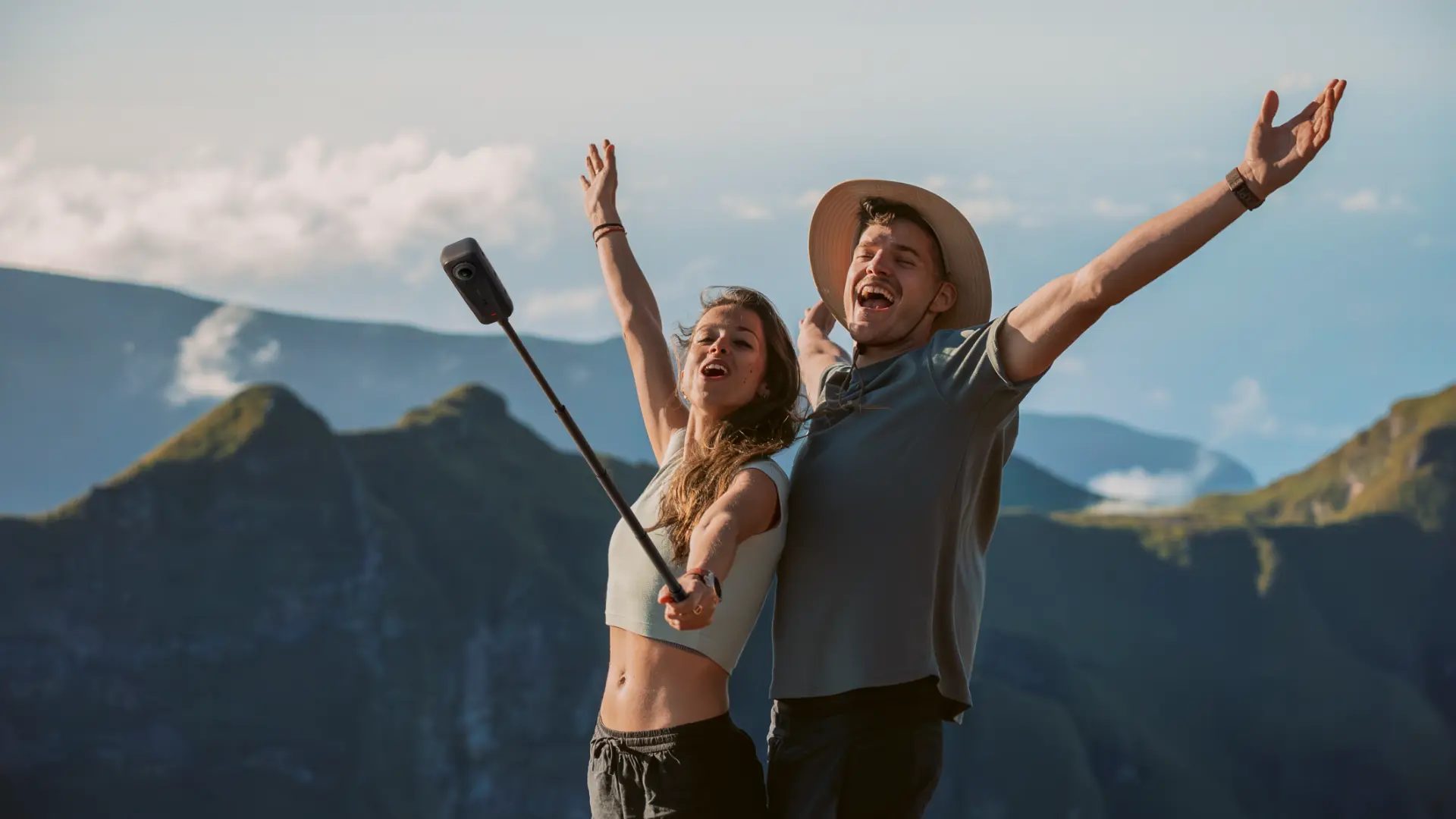 Couple on a mountain summit filming with the ultralight Insta360 X4 Air