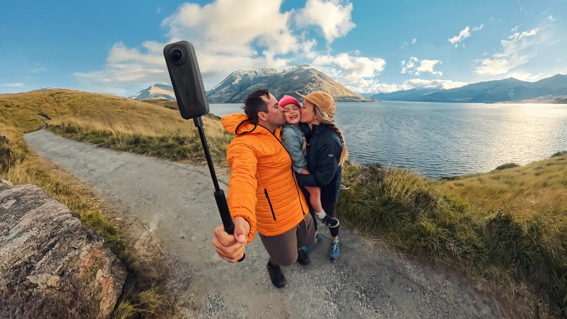 Family filming a 360 selfie at golden hour by a mountain lake with the X4 Air